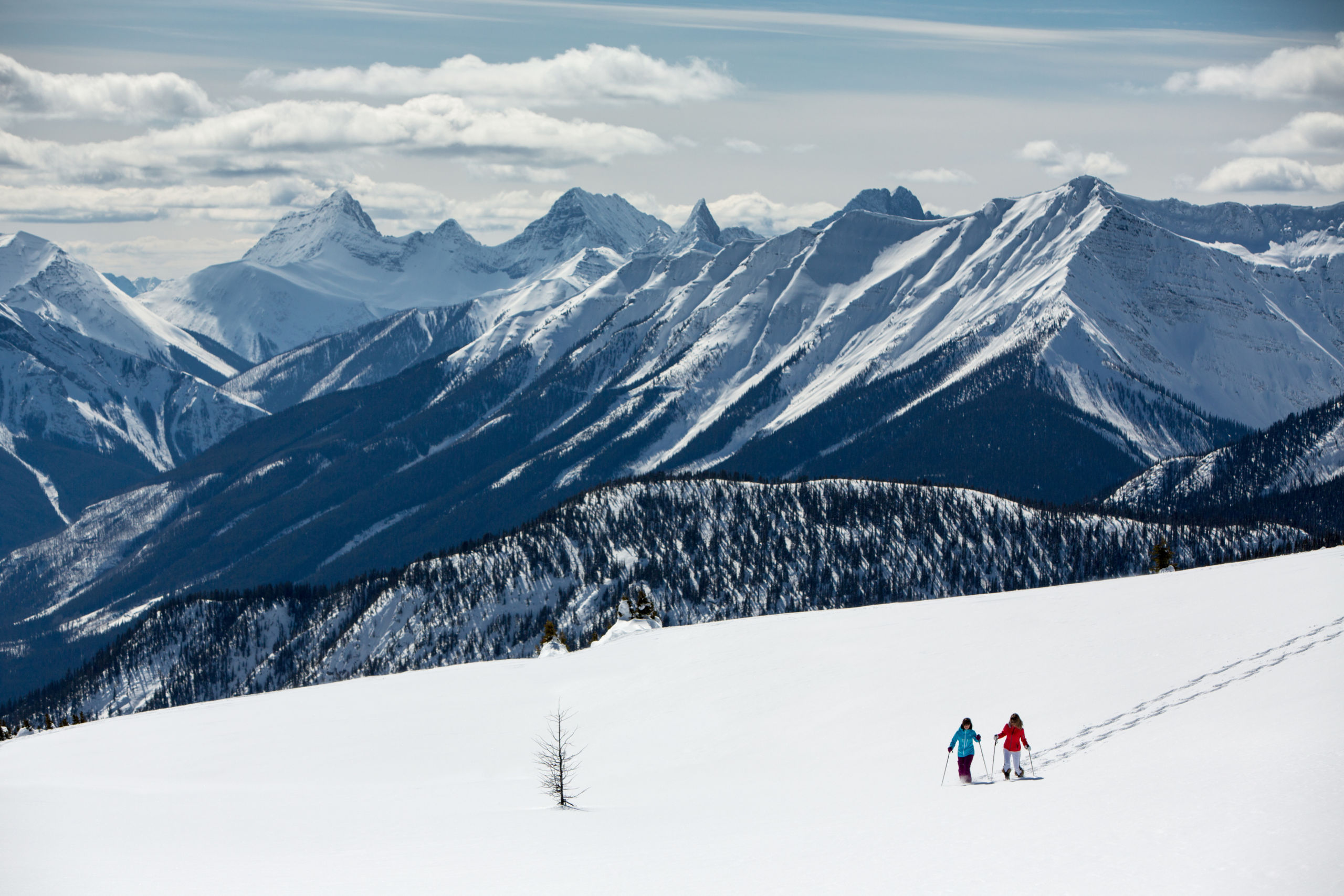 Deux personnes faisant de la raquette à Sunshine. Vue aérienne avec des montagnes en arrière-plan.