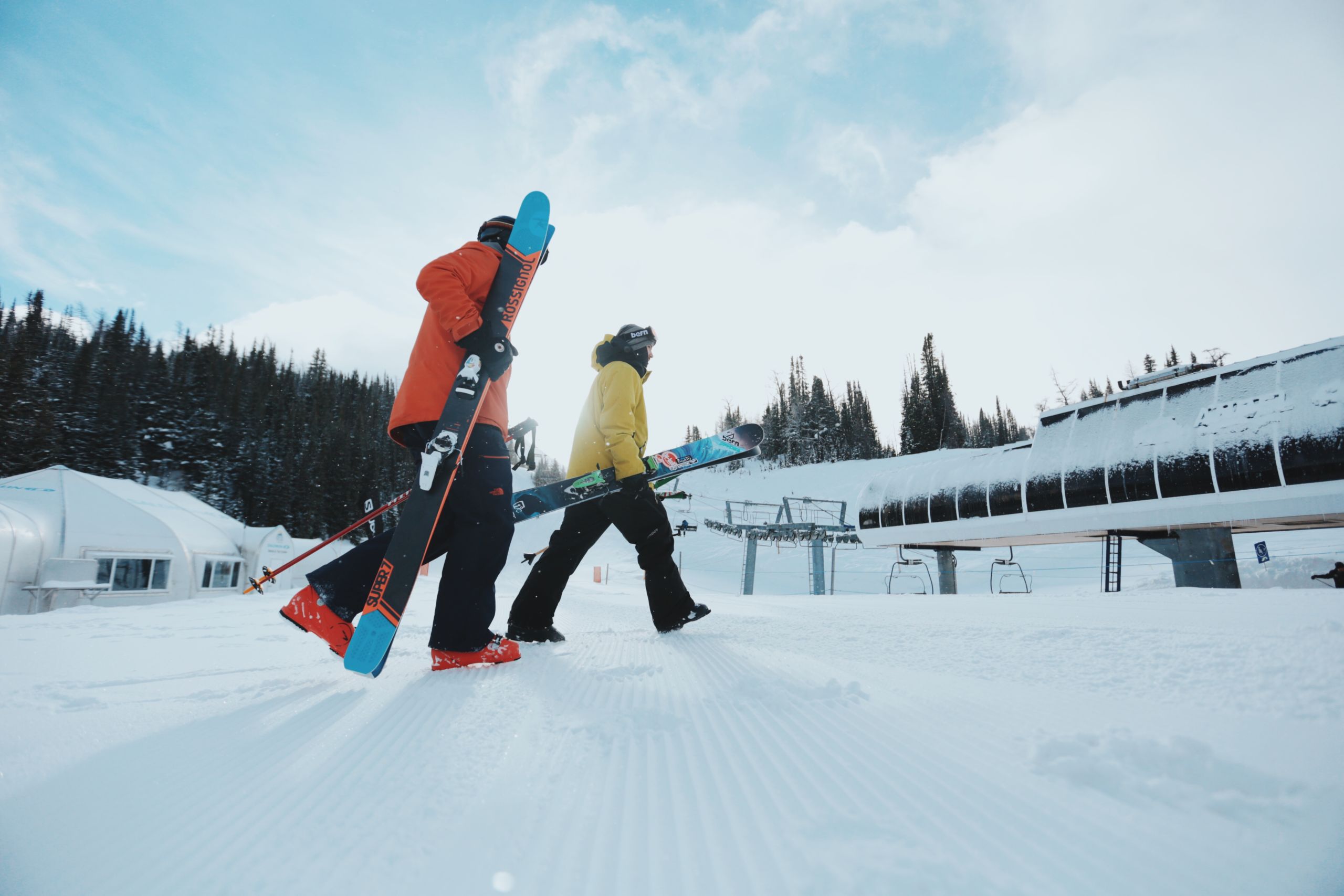 Deux personnes transportant leur équipement avant de skier à Sunshine Village, dans le parc national de Banff.